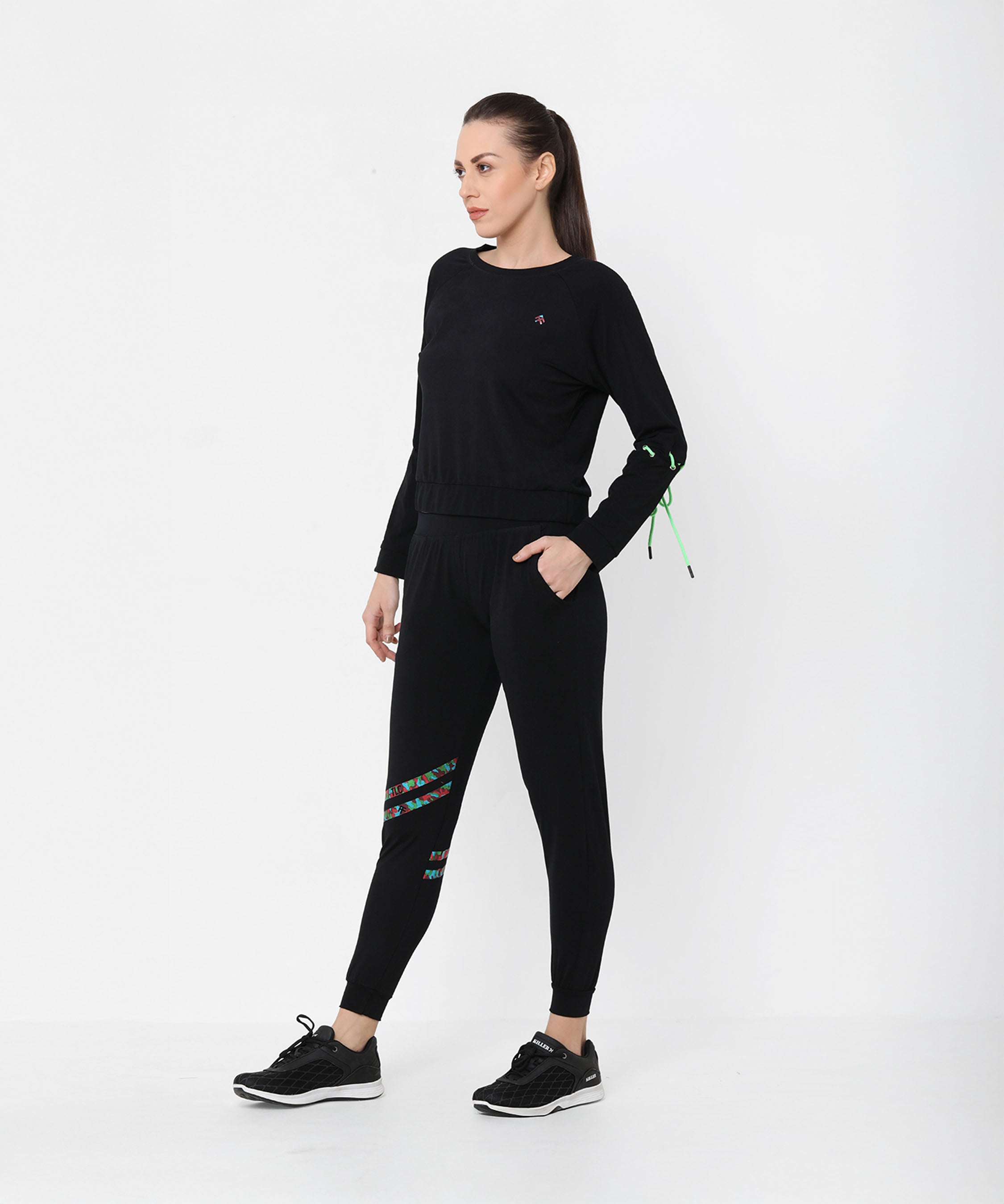 A woman models the Black Sweatshirt With Joggers, featuring colorful accents and iridescent camo tape, as she stands against a plain white background looking to the side.