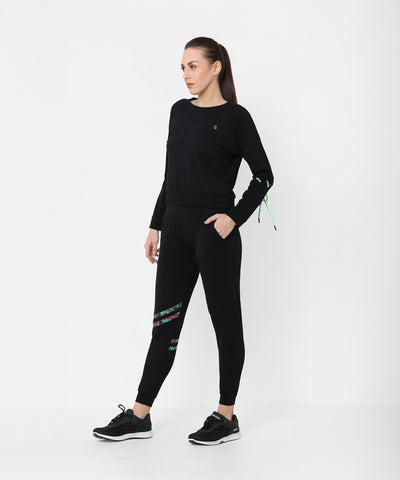 A woman models the Black Sweatshirt With Joggers, featuring colorful accents and iridescent camo tape, as she stands against a plain white background looking to the side.