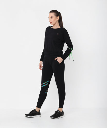 A woman models the Black Sweatshirt With Joggers, featuring colorful accents and iridescent camo tape, as she stands against a plain white background looking to the side.