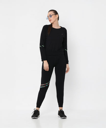 Woman wearing Black Sweatshirt With Joggers, featuring iridescent camo tape and sneakers, poses against a plain white background.