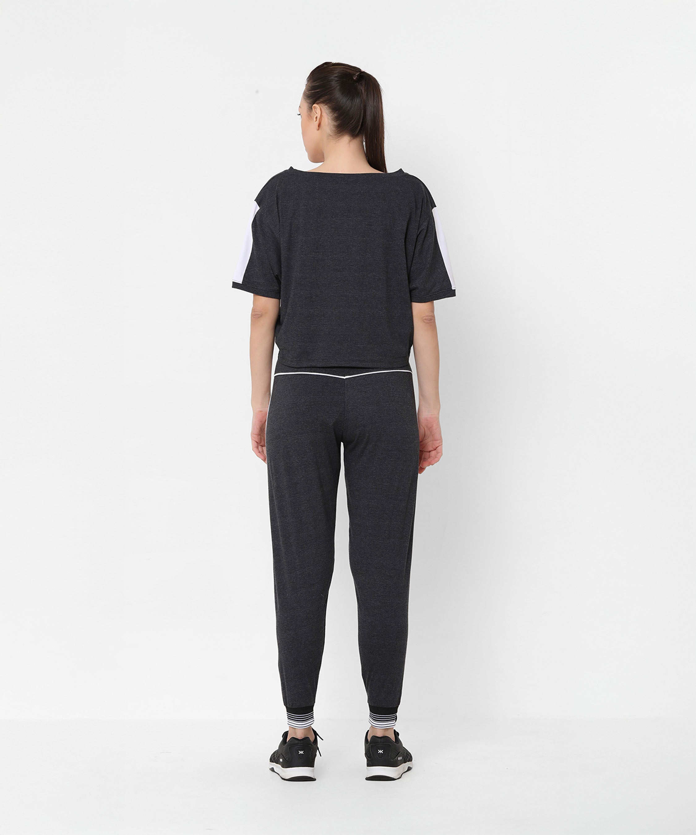 Woman wearing the Melange Dark Grey Set joggers and a comfort fit top, standing with her back to the camera against a white background.