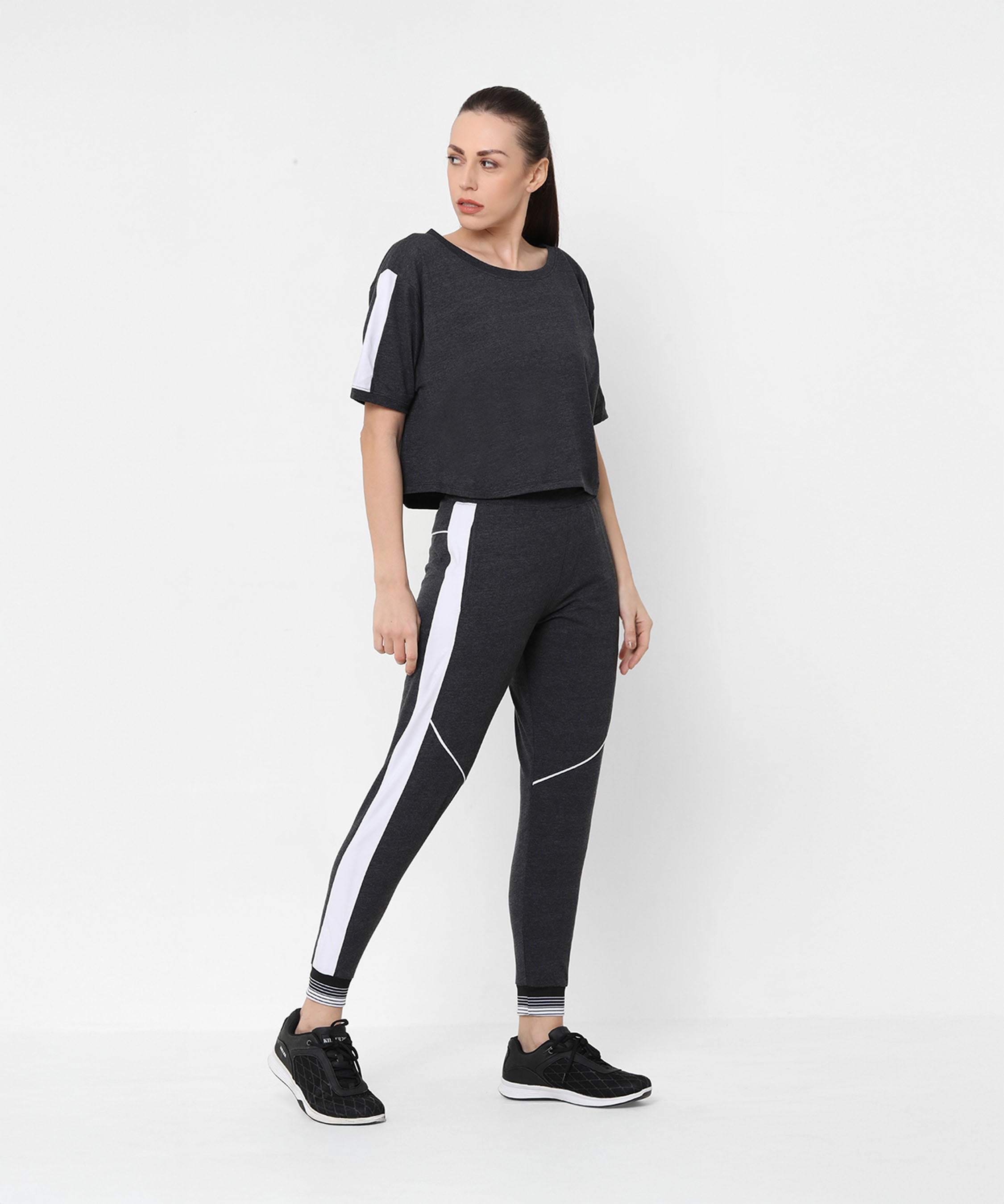 Woman wearing the Melange Dark Grey Set, featuring joggers and a comfort fit top, stands against a plain white background.