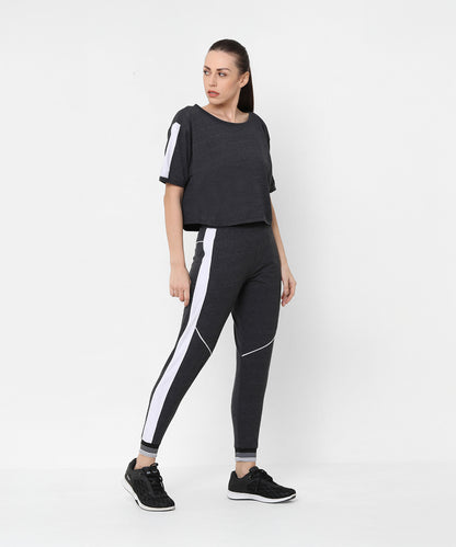 Woman wearing the Melange Dark Grey Set, featuring joggers and a comfort fit top, stands against a plain white background.
