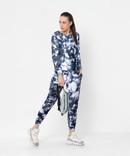 Woman wearing the Tie and Dye Tracksuit Set in blue and white, featuring signature joggers, holding a bag against a plain white background.