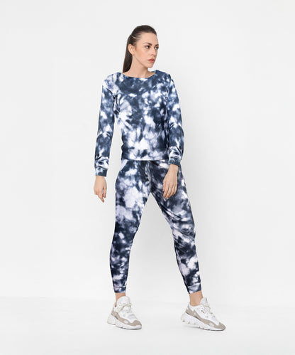 Woman wearing a Tie and Dye Tracksuit Set with white sneakers, standing against a white background.