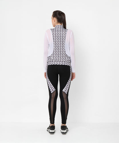 Woman facing away in athleisure style, wearing the Esther Jacket With Leggings—a printed net jacket with mesh sleeves and matching black leggings featuring sleek mesh panels.