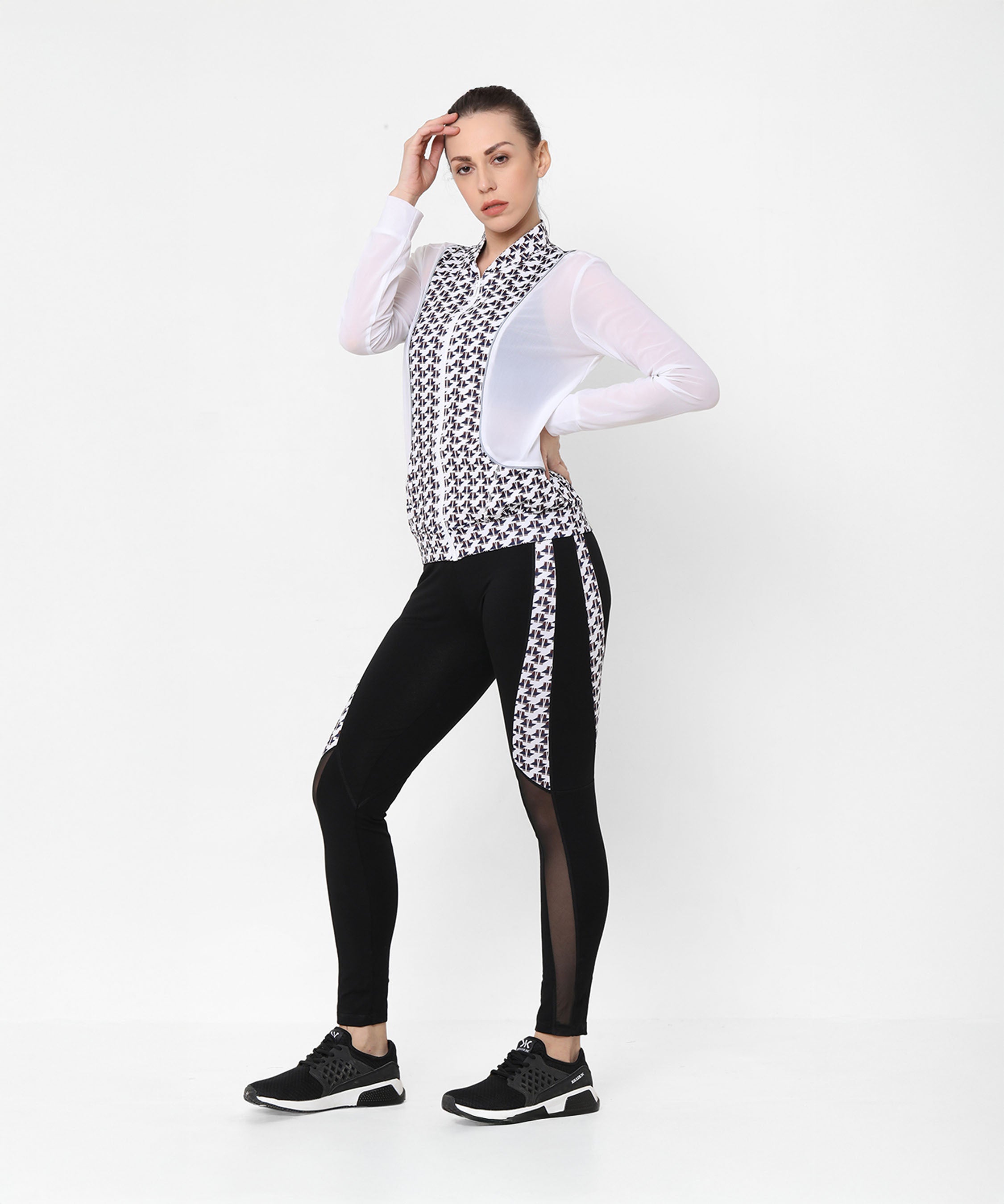 A woman poses confidently in the Esther Jacket With Leggings athleisure set, wearing a stylish black and white printed net jacket with matching leggings.