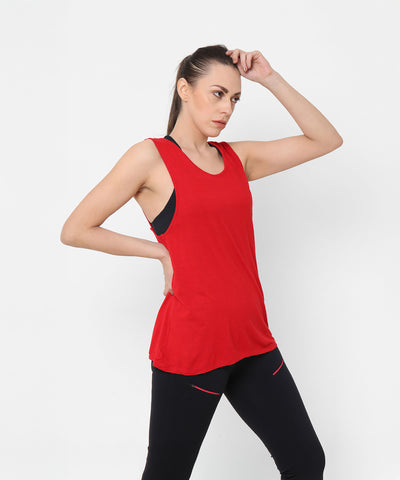 A woman in a Red Tank Top With Overlap Back and black leggings poses confidently, placing one hand on her hip while the other touches her head.