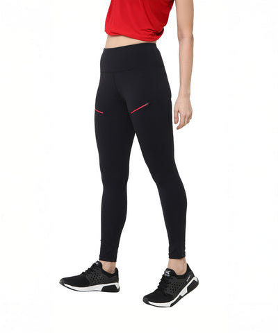 A person wearing a red top, Black Leggings With Zip featuring zippered pockets and red accents, and black athletic shoes stands on a white background.