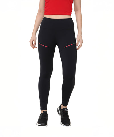 A woman stands against a white background wearing Black Leggings With Zip featuring zippered pockets and red accents, paired with a red crop top and black sneakers.