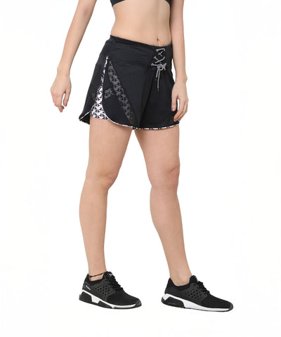 A woman wearing Sammy mesh shorts with a tie-up waistband, black sneakers, and a crop top stands against a white background.