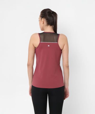 Woman stands with her back to the camera, wearing the Punch Pink Racer Back Top featuring black mesh panel detail.