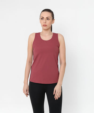 A woman wears the Punch Pink Racer Back Top, featuring mesh panel detailing, along with black leggings as she stands against a plain white background.