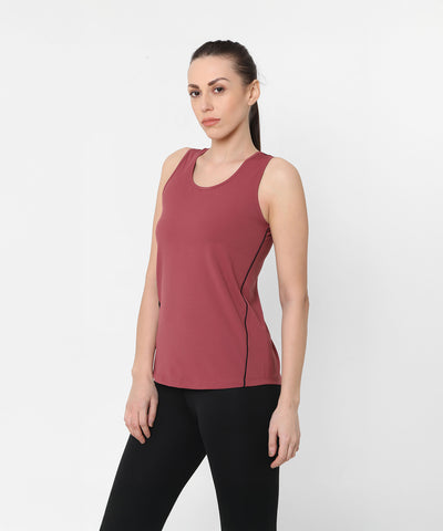 A woman wearing the Punch Pink Racer Back Top with a mesh panel and black leggings stands against a plain white background.