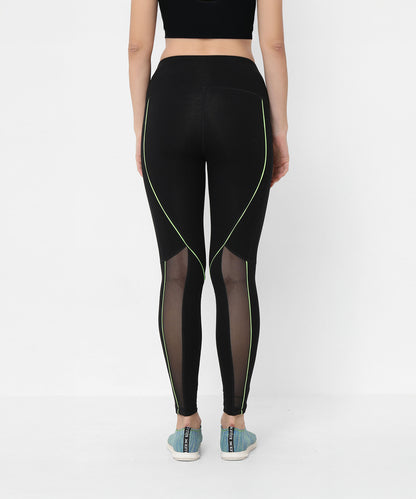 Woman wearing Fab Fit Neon Pop Leggings featuring mesh panels and a high-rise waistband, styled with a black crop top and blue sneakers.