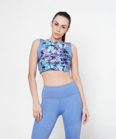 Woman wearing the Lia Crop Top and blue leggings stands against a plain white background, highlighting an active lifestyle.