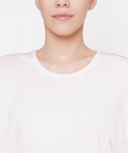 A woman wearing a light pink round neck T-shirt made of moisture-wicking mesh fabric, shown from the shoulders up with a neutral facial expression.