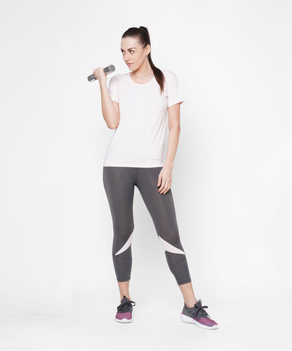 Woman in workout clothes wears Classic Capri in grey, featuring a thick waistband, and holds a dumbbell while standing against a plain white background for that fab fit look.