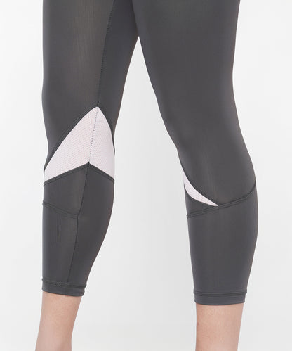 Close-up of a person wearing the Classic Capri black athletic leggings with white mesh panels behind the knees and a thick waistband for comfort.