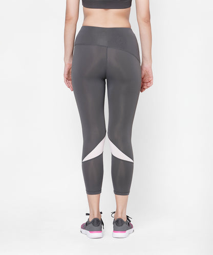 Person wearing Classic Capri in grey with white accents, paired with a gray sports top and sneakers, shown from the back. Features a thick waistband for extra comfort.