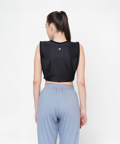 Woman with a ponytail shown from the back, wearing a Black Crop Top With Mesh Overlay and light blue pants.