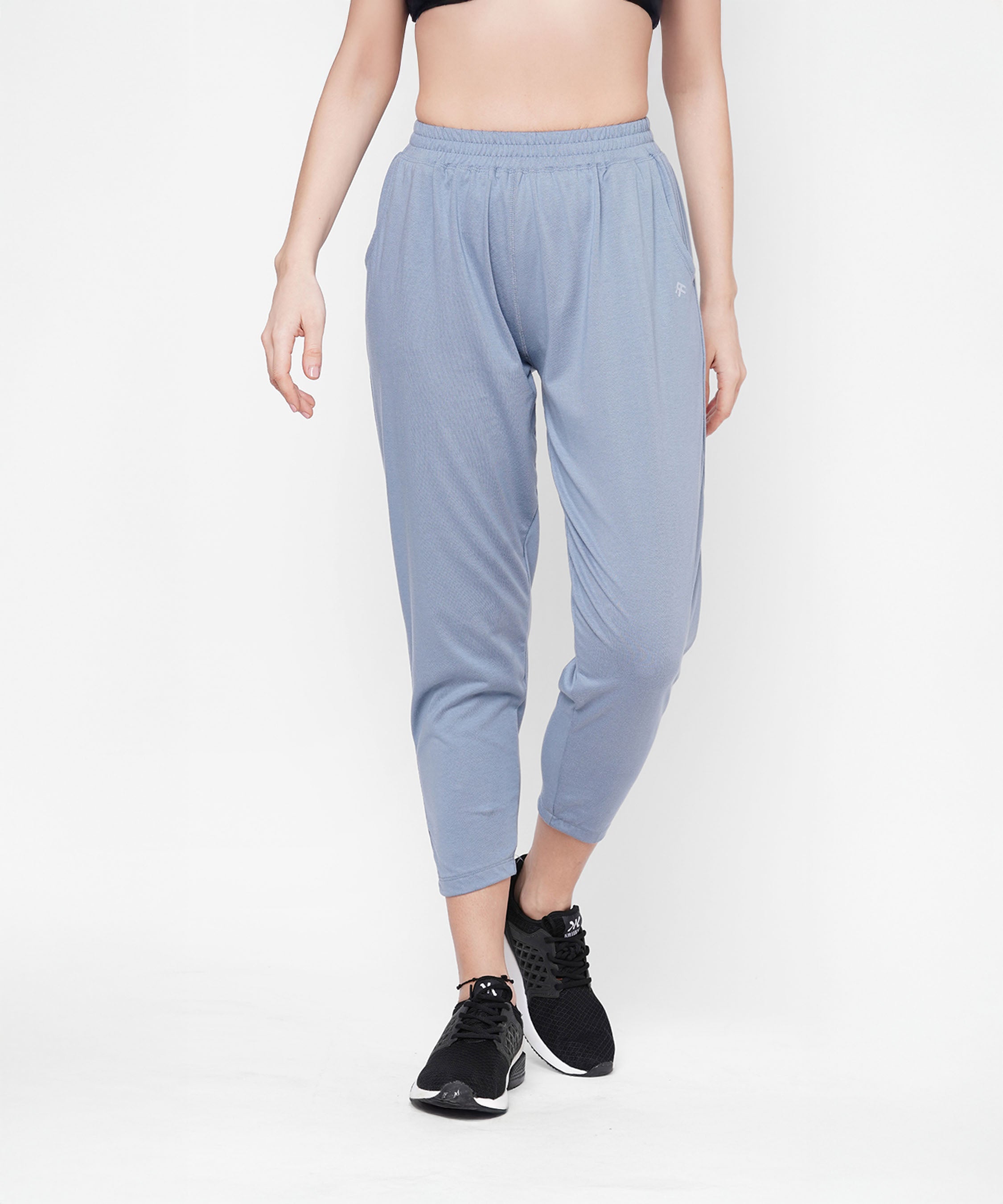 A person models Grey Yoga Pants, paired with a black crop top and black sneakers, standing against a white background.