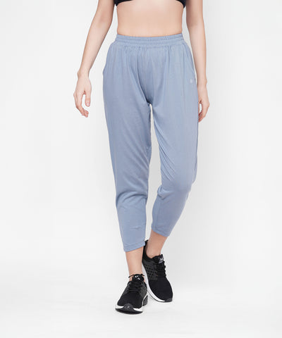 A person models Grey Yoga Pants, paired with a black crop top and black sneakers, standing against a white background.