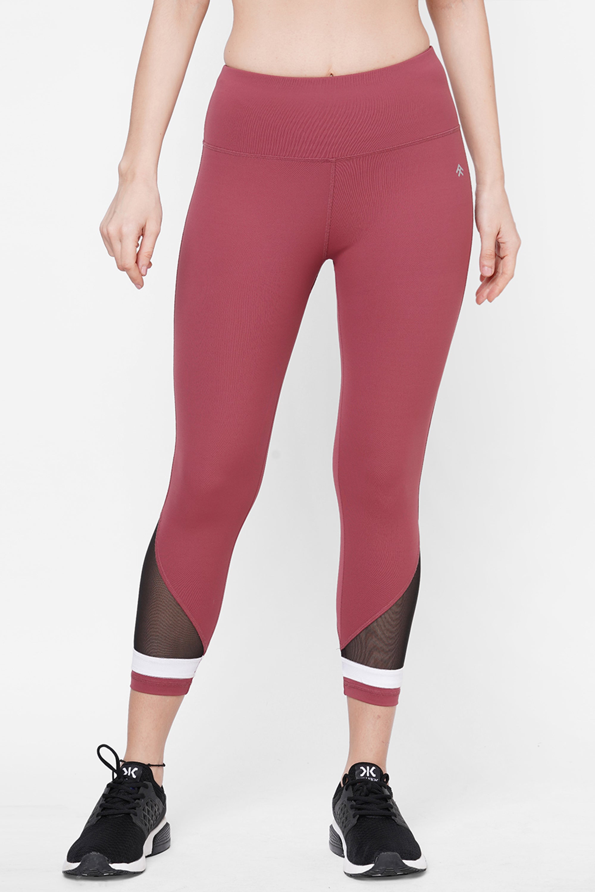 Person wearing Punch pink Capri leggings featuring a compression fit waistband and mesh panels, paired with black sneakers against a white background—a perfect choice for stylish workout clothing.