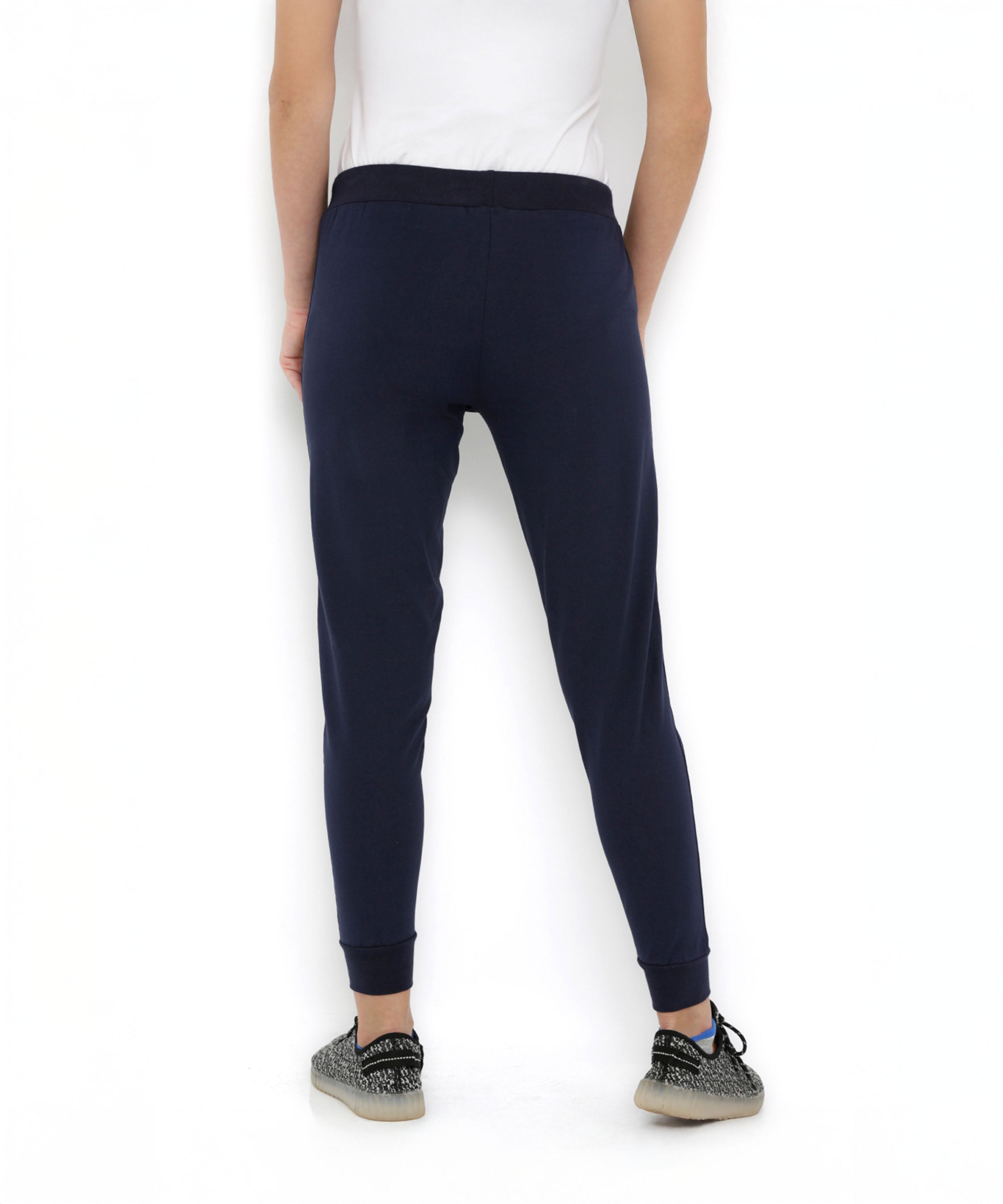 A person shown from the back, wearing Blue Classic Joggers TLC04 with a slim tapered fit, a white t-shirt, and patterned sneakers, set against a white background.
