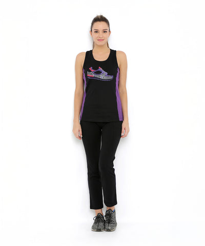 A woman stands against a white background wearing Regular Fit Trackpants TLC05 in black and purple with a branded waistband, paired with gray sneakers.