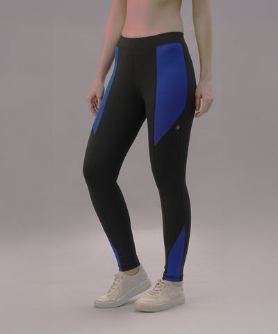 A person wears Black and Blue Pants made from four-way stretch fabric with white sneakers, standing against a plain background.