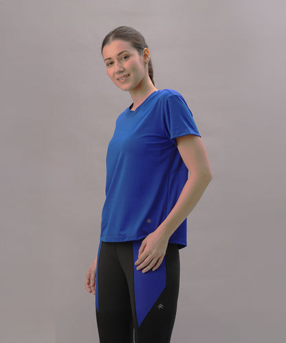 Smiling woman wears the Blue Comfort T-Shirt and black leggings with blue panels, standing against a plain backdrop—ideal for an active lifestyle.