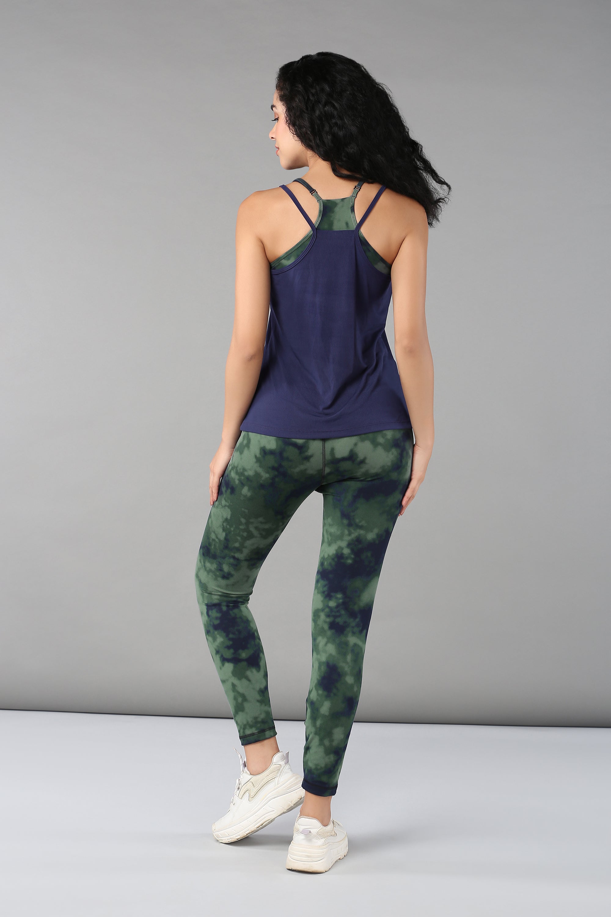 Woman in a Tie & Dye Bra T shirt and green tie-dye leggings, standing with her back to the camera.