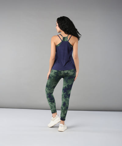 A woman stands with her back to the camera in a navy tank top and Tie & Dye Leggings, highlighting a stylish workout wardrobe crafted from stretchy fabric.