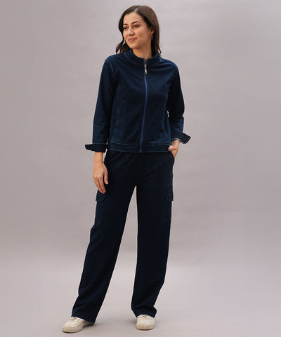 A woman stands against a light background, wearing the Blue Denim Wash Jacket with matching pants and one hand in her pocket.