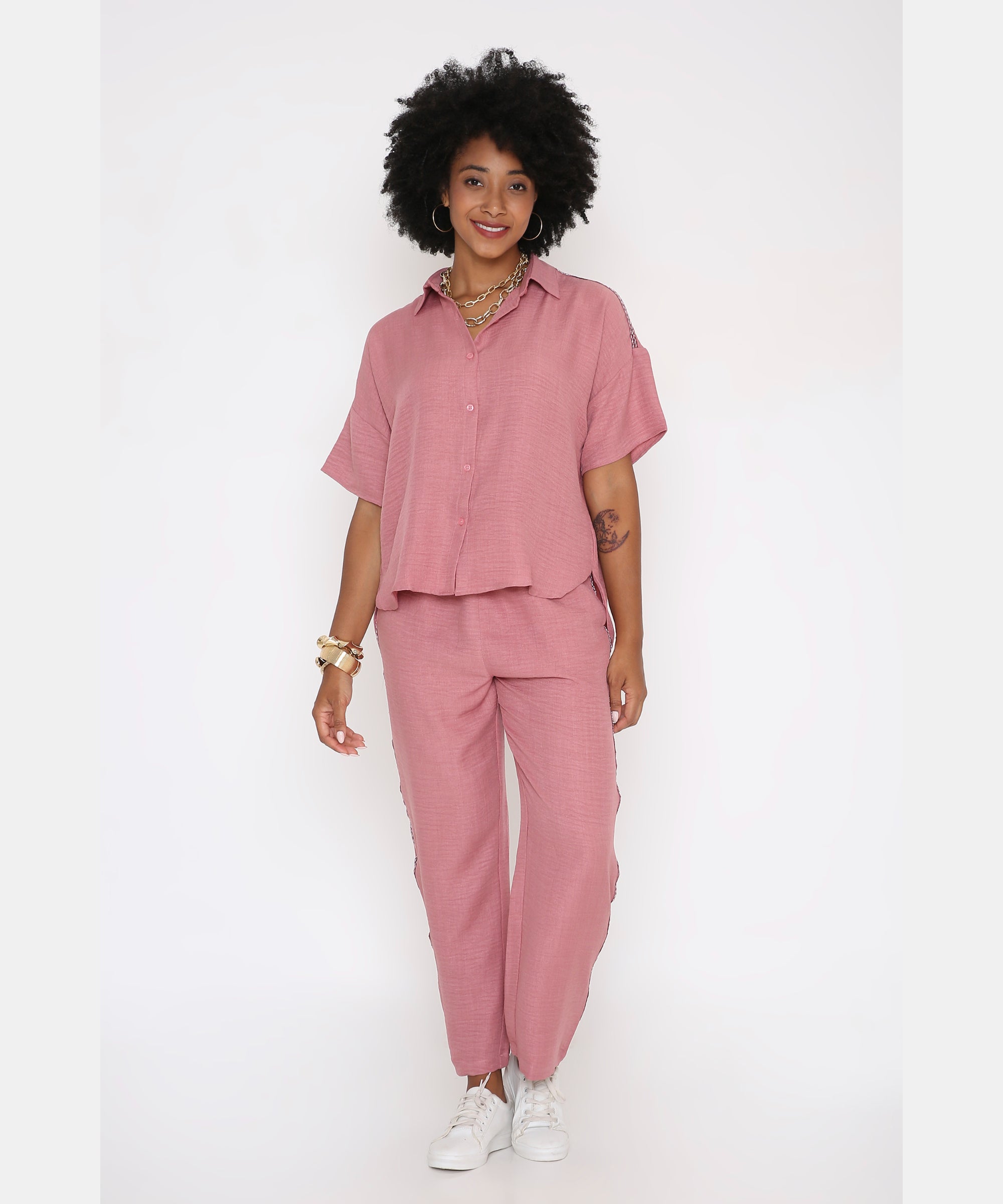 A woman stands and smiles in the Vintage Pink Loose Shirt and Pant Cord Set, paired with white sneakers.
