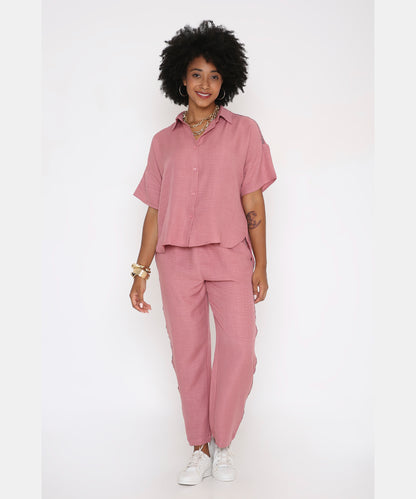 A woman stands and smiles in the Vintage Pink Loose Shirt and Pant Cord Set, paired with white sneakers.