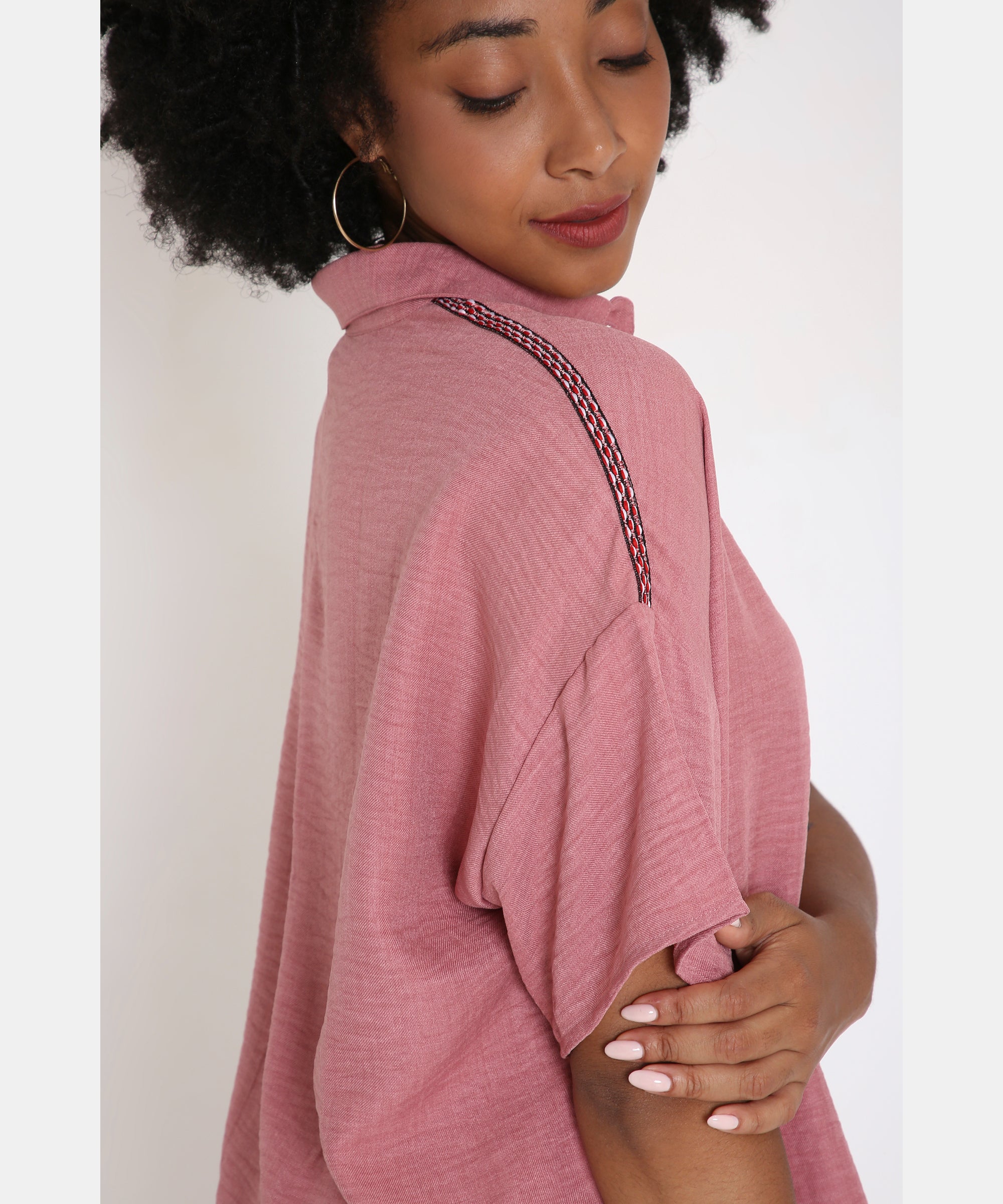Woman wearing the Vintage Pink Loose Shirt and Pant Cord Set, featuring a short-sleeve top with decorative shoulder detail, looks down and gently touches her arm.