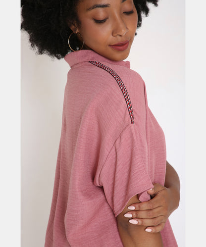 Woman wearing the Vintage Pink Loose Shirt and Pant Cord Set, featuring a short-sleeve top with decorative shoulder detail, looks down and gently touches her arm.