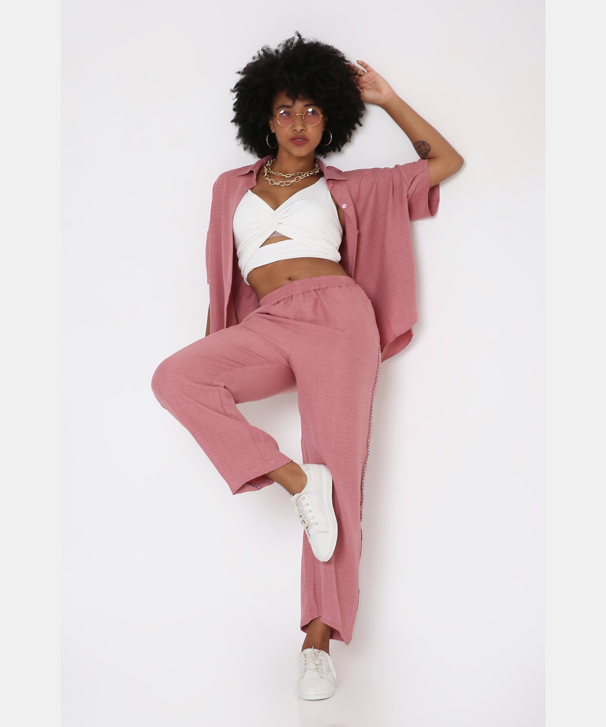 Model wears the Vintage Pink Loose Shirt and Pant Cord Set with wide-leg pants and white sneakers, posing against a white background with one leg raised.