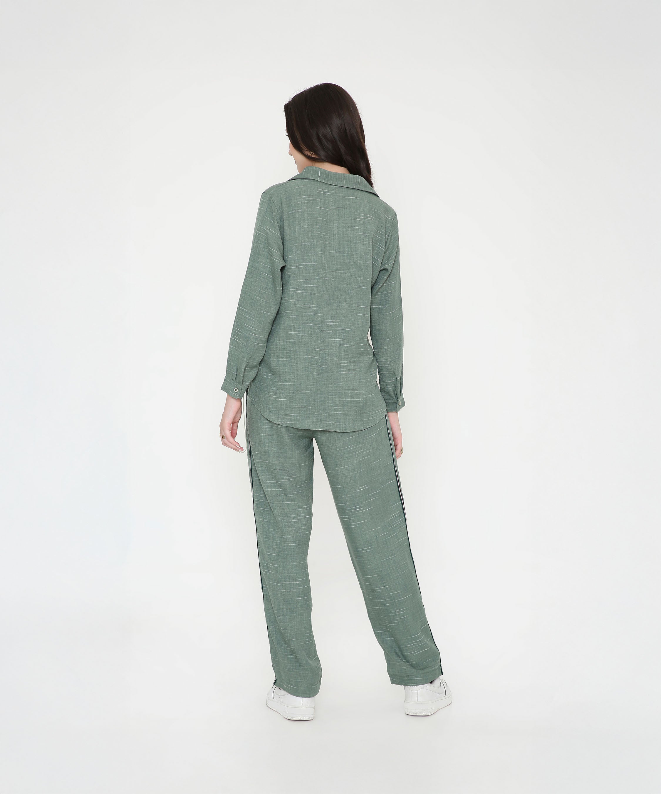 A woman models the Moss Green Breezy Cord Set, standing with her back to a plain white background and highlighting the set’s relaxed fit.