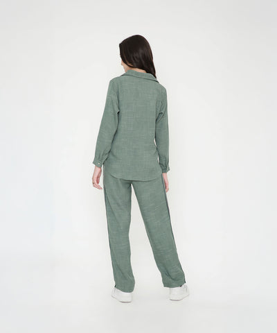 A woman models the Moss Green Breezy Cord Set, standing with her back to a plain white background and highlighting the set’s relaxed fit.