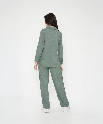 A woman models the Moss Green Breezy Cord Set, standing with her back to a plain white background and highlighting the set’s relaxed fit.