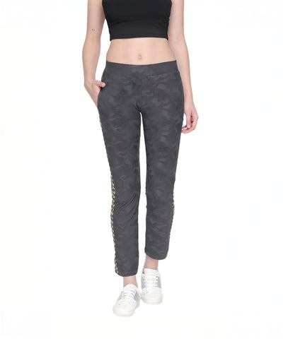 Woman in a black crop top and Self Printed Grey TrackPants with hands in pockets, paired with white sneakers—a stylish athleisure look for women.