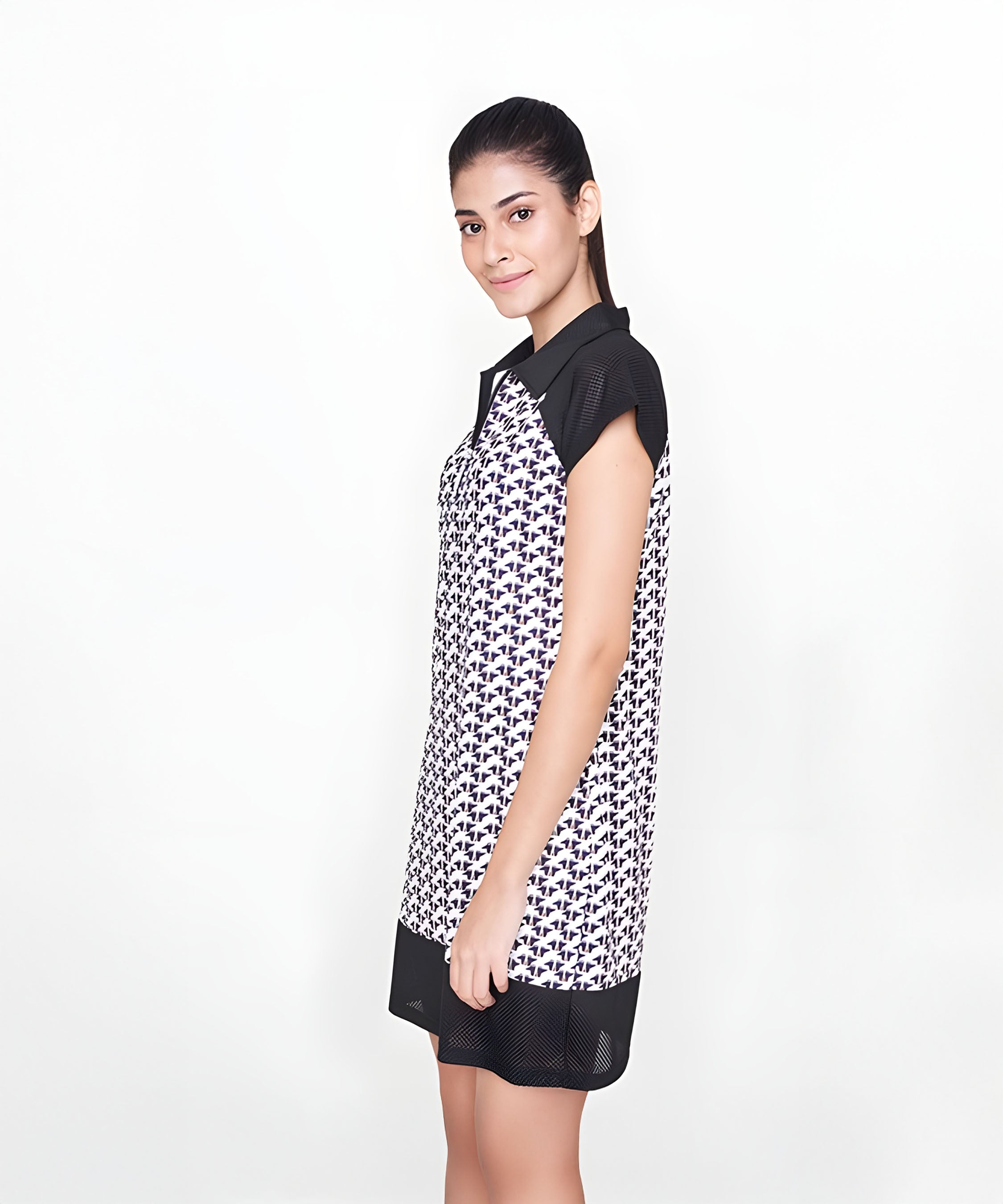 A woman stands sideways in a Black Dress with a white collar, crafted from polyester—an ideal effortless airport look—against a simple background.