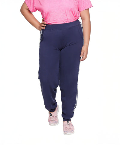 Person wears a pink shirt, pink sneakers, and Joggers With Side Stripe - Plus Size in navy blue on a white background.