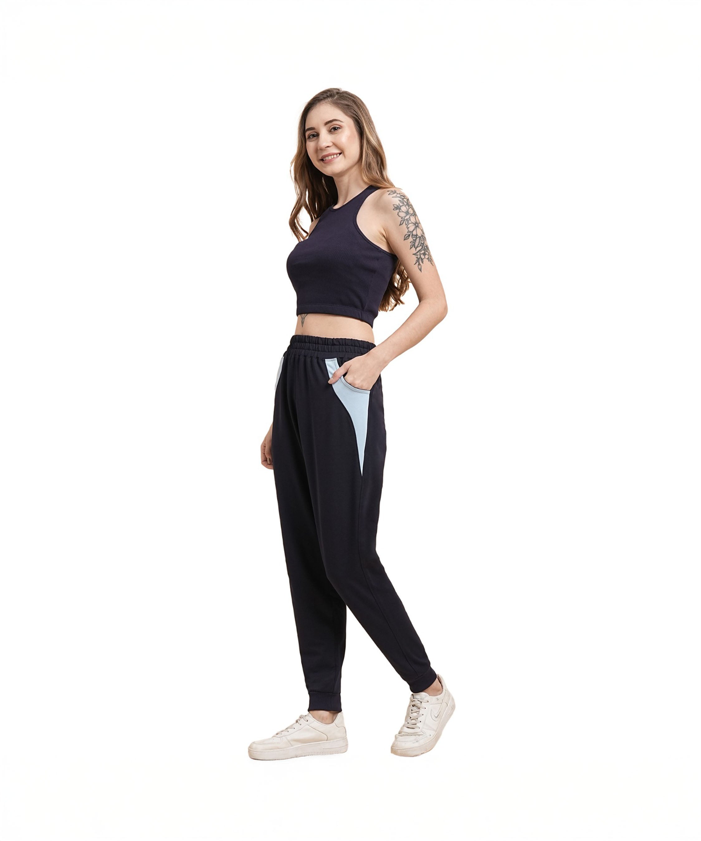 Woman wearing Tuna Active Navy Blue Joggers, smiling with her hands in her pockets, standing against a white background.