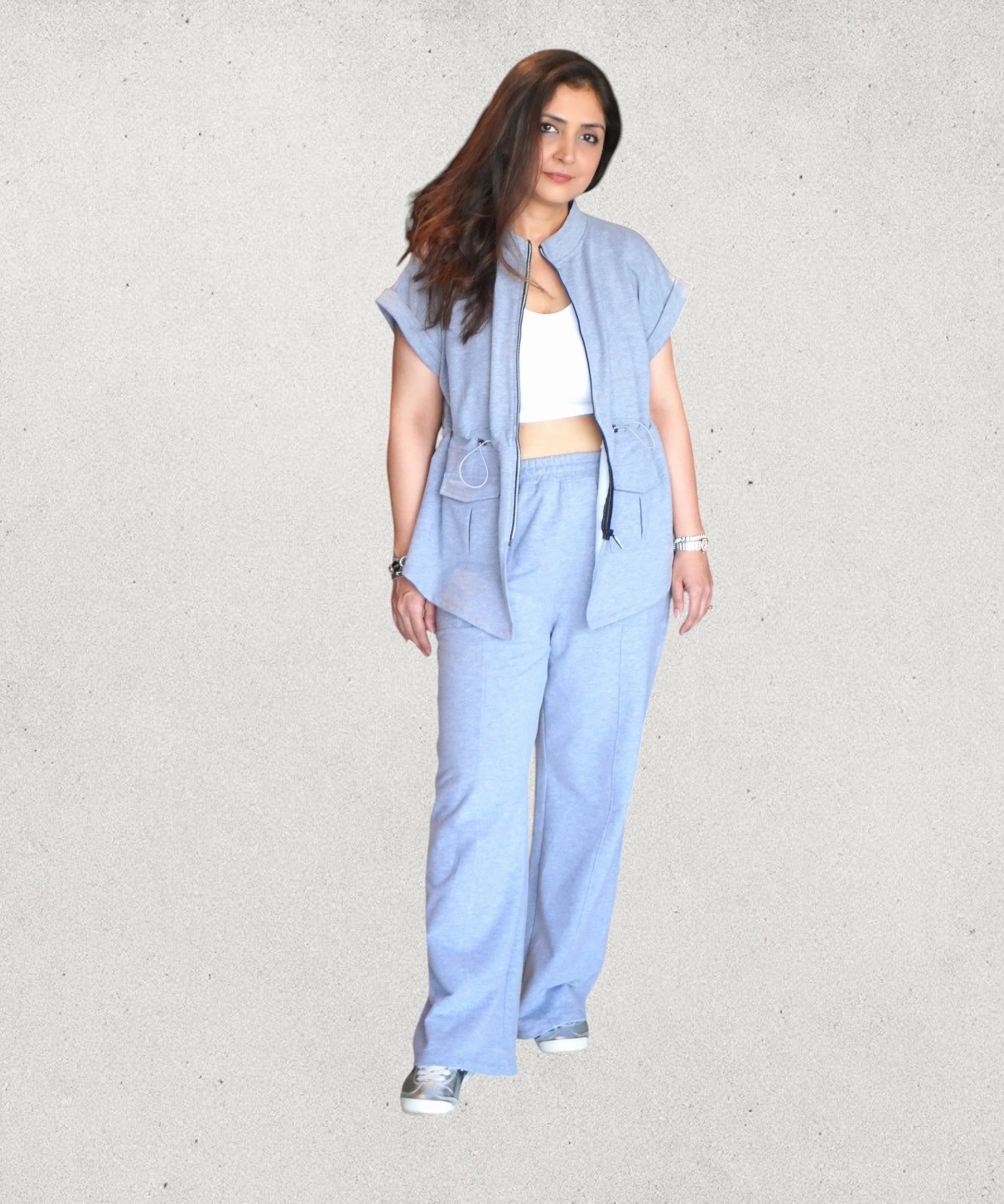 Tuna Active light blue zippered utility jumpsuit with wide legs and patch pockets, worn by a woman with a white crop top and sneakers.