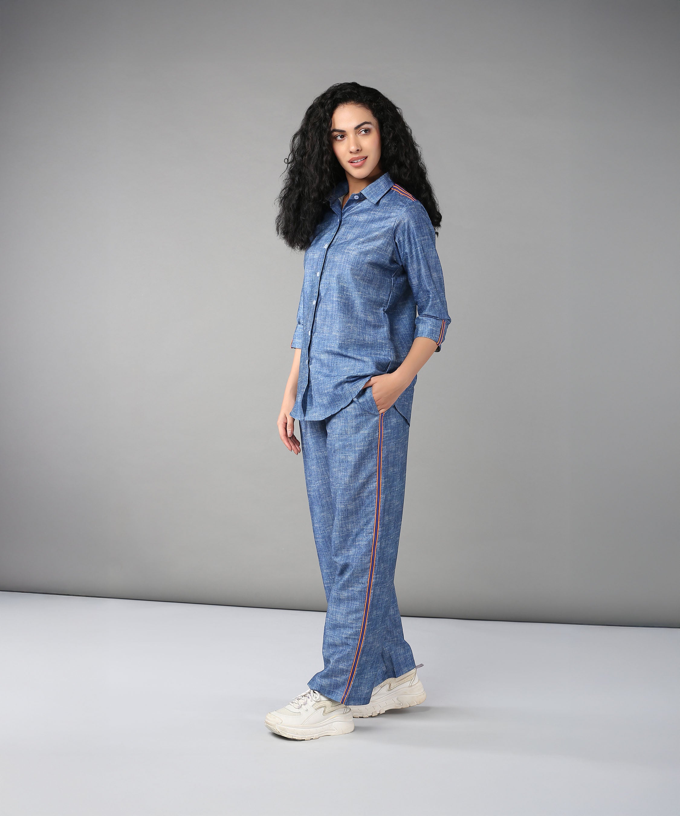 Woman models the Denim Linen Co-Ord Set—a high-quality denim ensemble with a relaxed fit shirt and red piping—posing in a studio with a gray backdrop.