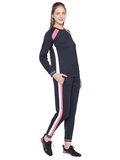 Woman in a Full Sleeve Navy Blue Round Neck Sweatshirt by Tuna London, paired with striped tracksuit and black sneakers—perfect for a workout session.